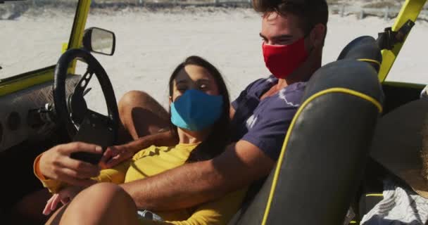 快乐的高加索夫妇 戴着口罩坐在沙滩婴儿车里自拍 夏季度假路上的海滩停留时间 在考拉病毒大流行期间 — 图库视频影像