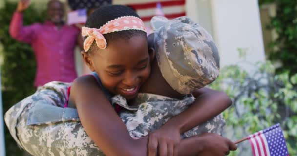 非裔美国军人的父亲抱着笑着的女儿 身后挂着家人和美国国旗 回家的士兵 后备箱 — 图库视频影像