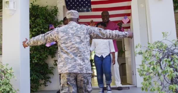 アフリカ系アメリカ人兵士の父は興奮した家族の前にアメリカ国旗を掲げて家を抱き上げた 兵士は家族の元に戻り — ストック動画