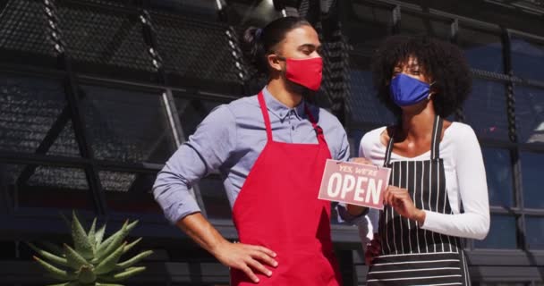 フェイスマスクをした多様なカフェワーカーが看板を開いていた コロナウイルスの大流行期の小規模な独立系企業は — ストック動画