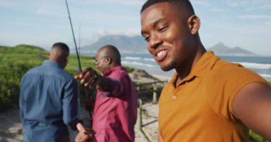 Afrika kökenli Amerikalı kıdemli baba ve iki genç oğul sahilde balık tutup sohbet ediyorlar. Sağlıklı açık hava aile birlikte zaman geçirir..