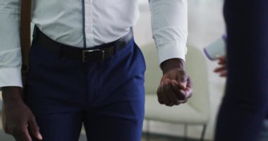 Afrika kökenli Amerikalı iş adamının, ofise vardıklarında sıcaklığını ölçtürmesi. Covid 19 Coronavirüs salgını sırasında modern ofiste çalışan iş adamları..