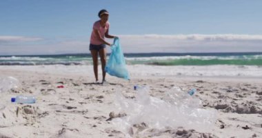 Plajda plastik atık toplayan Afrikalı Amerikalı kadın. ekoloji çevre koruma ve geri dönüşüm kavramı