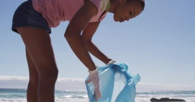 Plajda plastik atık toplayan Afrikalı Amerikalı kadın. ekoloji çevre koruma ve geri dönüşüm kavramı