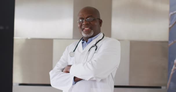 Smiling African American Senior Male Doctor Wearing White Crossing His — Stock Video