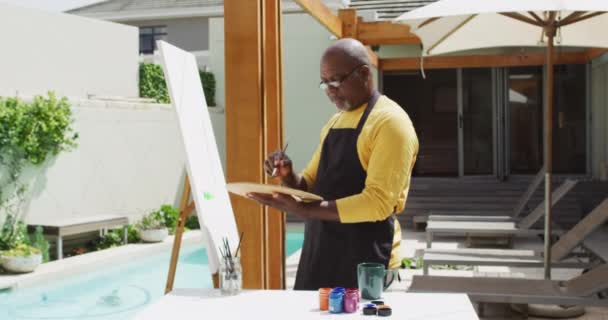 アフリカ系アメリカ人の先輩がテラスに立って絵を描いている 引退趣味やアウトドアレジャータイム — ストック動画