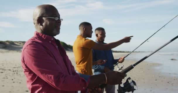 Afro Amerikaanse Senior Vader Tweeling Tienerzonen Staan Een Strand Vissen — Stockvideo