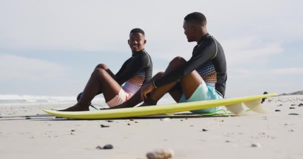 快乐的非洲裔美国少年孪生兄弟坐在冲浪板旁聊天 健康的户外运动时间 — 图库视频影像