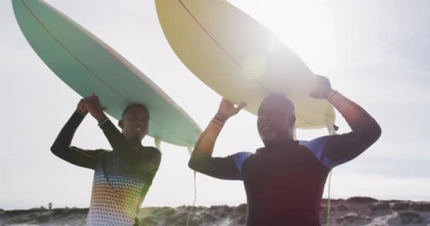 非裔美国人的父亲和十多岁的儿子站在海滩上 手握冲浪板 高谈阔论 健康的户外运动时间 — 图库视频影像