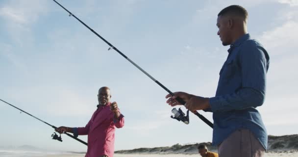 Afro Amerikaanse Senior Vader Twee Tienerzonen Staan Een Strand Vissen — Stockvideo
