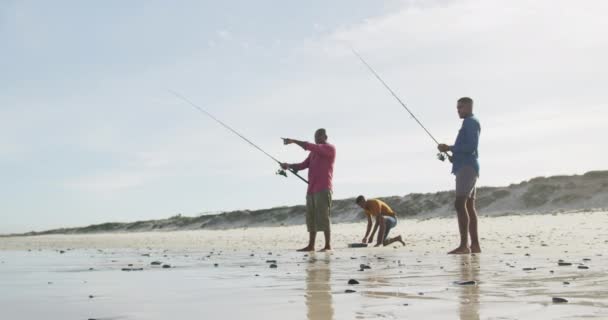 非裔美国人的父亲和两个十几岁的儿子站在海滩上钓鱼聊天 健康的户外运动时间 — 图库视频影像