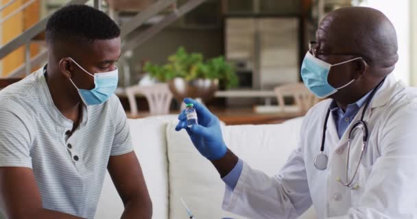 非洲裔美国高级男医生在家里给男病人注射眼镜蛇疫苗 戴口罩 食管癌大流行期间在家中隔离的医疗保健 — 图库视频影像