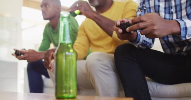 Padre Afroamericano Hijos Gemelos Adolescentes Sentados Sofá Jugando Televisión Bebiendo — Vídeos de Stock