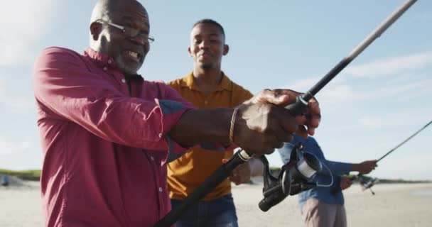 非裔美国人的长大成人父亲和两个年幼的儿子站在海滩上钓鱼聊天 健康的户外运动时间 — 图库视频影像