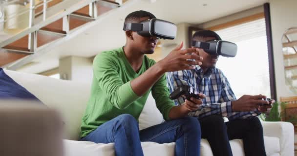 非洲裔美国少年双胞胎兄弟坐在沙发上 用Vr耳机和玩电脑游戏 隔离期间家庭在家中的闲暇时间 — 图库视频影像