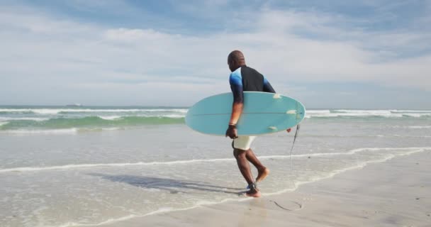 Afroamerikansk Senior Man Som Går Strand Med Surfbräda Och Springer — Stockvideo