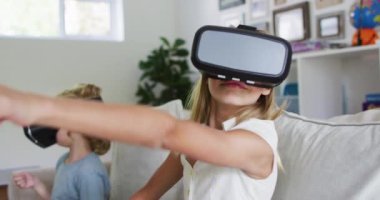 Beyaz erkek ve kız kardeşler evdeki kanepede otururken kulaklık takarak el kol hareketi yapıyorlar. Aile, birliktelik ve mutluluk kavramı