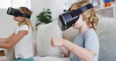 Beyaz erkek ve kız kardeşler evdeki kanepede otururken kulaklık takarak el kol hareketi yapıyorlar. Aile, birliktelik ve mutluluk kavramı