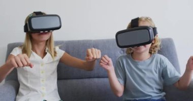 Beyaz erkek ve kız kardeşler evdeki kanepede otururken kulaklık takarak el kol hareketi yapıyorlar. Aile, birliktelik ve mutluluk kavramı