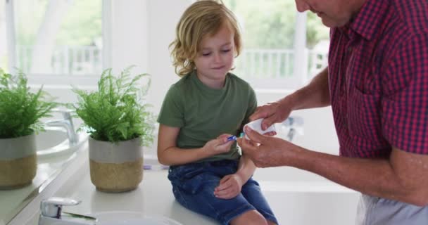 白人祖父帮助孙子在家里的牙刷上涂牙膏 团聚和幸福的概念 — 图库视频影像