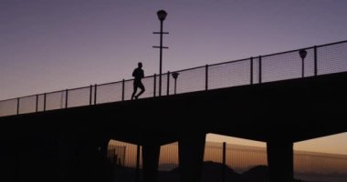 Akşamları köprüde koşan bir adamın silueti. fitness, aktif ve sağlıklı yaşam tarzı konsepti.