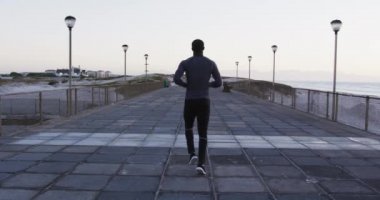 Afrika kökenli Amerikalı bir adamın açık havada egzersiz yaptığını deniz kenarında koştuğunu gördüm. fitness, aktif ve sağlıklı yaşam tarzı konsepti.