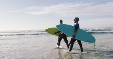 Kıdemli Afro-Amerikan çift sahilde sörf tahtasıyla yürüyor. sağlıklı açık hava eğlence zamanı deniz kenarında.
