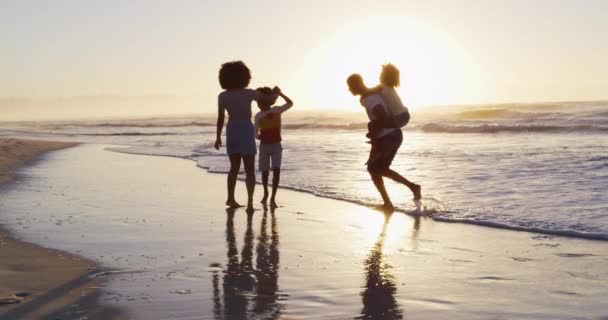 ビーチでの日没の間にアフリカ系アメリカ人の家族が一緒に楽しんでいます 家族旅行休暇のコンセプト — ストック動画