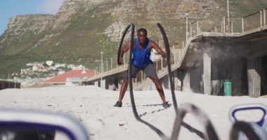 Odaklanmış Afro-Amerikan adam sahilde halatlarla savaşıyor. fitness, sağlıklı ve aktif yaşam tarzı konsepti.
