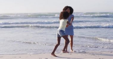 Afrikalı Amerikalı anne ve kızı sahilde oynuyorlar. sağlıklı açık hava eğlence zamanı deniz kenarında.