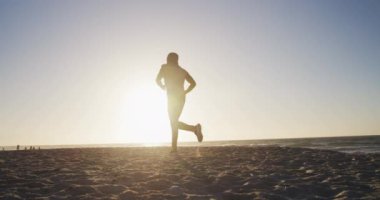 Plajda koşan Afrikalı Amerikalı bir adam, akşamları sahilde egzersiz yapıyor. fitness, sağlıklı ve aktif yaşam tarzı konsepti.