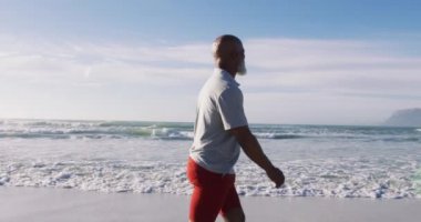 Kıdemli Afro-Amerikan adam sahilde yürüyor. sağlıklı açık hava eğlence zamanı deniz kenarında.