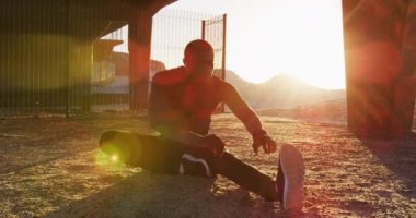 Odaklanmış Afrikalı Amerikalı adam bacaklarını açıyor, akşamları dışarıda egzersiz yapıyor. fitness, sağlıklı ve aktif yaşam tarzı konsepti.