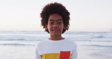 Sahilde dururken gülümseyen Afrikalı Amerikalı bir çocuğun portresi. Aile seyahati tatil eğlence konsepti