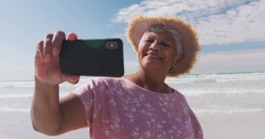 Sahilde akıllı telefonuyla selfie çeken son sınıf öğrencisi bir kadın. sağlıklı açık hava eğlence zamanı deniz kenarında.