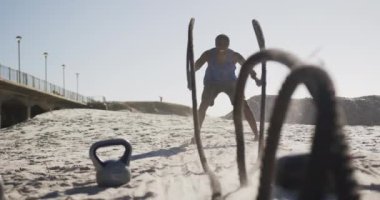 Odaklanmış Afro-Amerikan adam sahilde halatlarla savaşıyor. fitness, sağlıklı ve aktif yaşam tarzı konsepti.