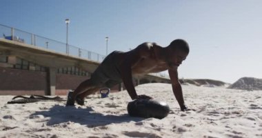 Topun üzerinde şınav çeken, dışarıda sahilde egzersiz yapan odaklanmış Afro-Amerikan bir adam. fitness, sağlıklı ve aktif yaşam tarzı konsepti.