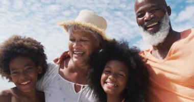 Sahilde gülümseyen torunları olan yaşlı çiftlerin portresi. sağlıklı açık hava eğlence zamanı deniz kenarında.