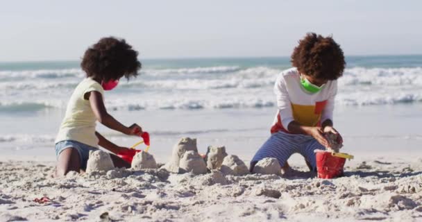 ビーチで砂遊びをするアフリカ系アメリカ人の子供たち コロナウイルスの間の海による健康的な屋外レジャー時間Covid 19パンデミック — ストック動画