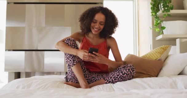 Mujer Afroamericana Sentada Cama Usando Teléfono Inteligente Sonriendo Permanecer Casa — Vídeos de Stock