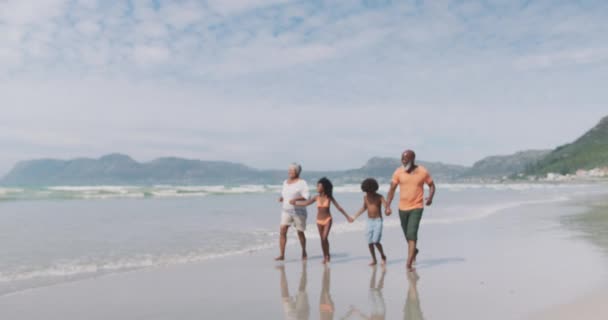 孫が歩いてビーチで手を握っている混合レースのシニアカップル 海による健康的な屋外レジャータイム — ストック動画