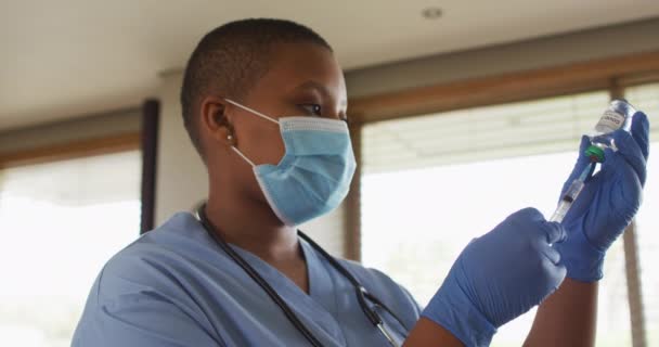 フェイスマスクを着用したアフリカ系アメリカ人女性医師は 患者のために咳止めワクチンを準備する コロナウイルスの専門医療従事者は19のパンデミックを克服しました — ストック動画