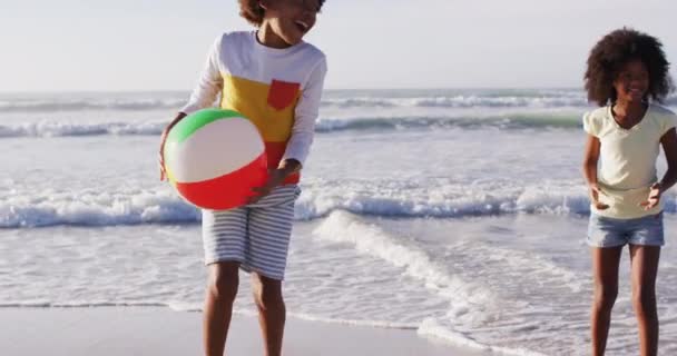 アフリカ系アメリカ人の母親と彼女の子供たちがビーチでボールで遊んでいる 海による健康的な屋外レジャータイム — ストック動画