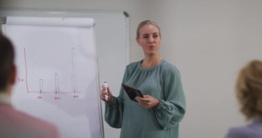 Beyaz panoda duran beyaz iş kadını meslektaşlarına tablet kullanarak sunum yapıyor. Modern bir ofiste iş..