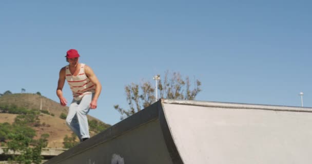 白人男性は晴れた日にスケートボードに乗ってジャンプします 夏にスケートパークに遊びに来て — ストック動画