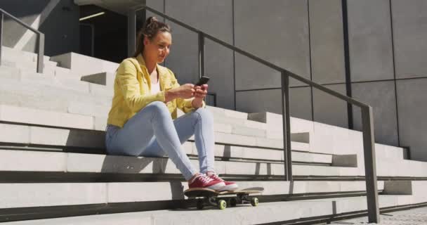 Biała Kobieta Siedząca Schodach Deskorolką Używająca Smartfona Słoneczny Dzień Przesiadywanie — Wideo stockowe