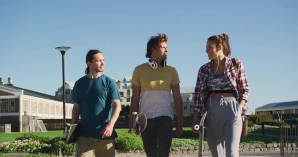 幸せな白人女性と2人の男性の友人は晴れた日に一緒に時間を過ごす 夏にスケートパークに遊びに来て — ストック動画