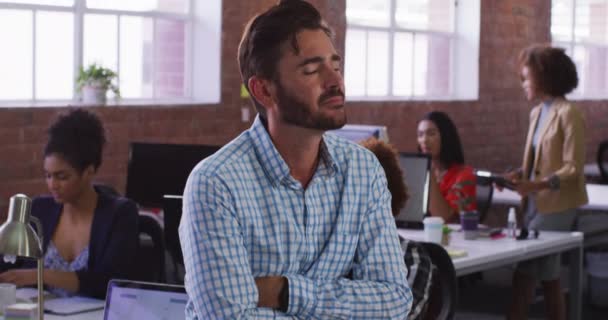 バックグラウンドで多様な同僚とオフィスの部屋で笑顔に座って白人ビジネスマン 独立した創造的なデザインビジネス — ストック動画