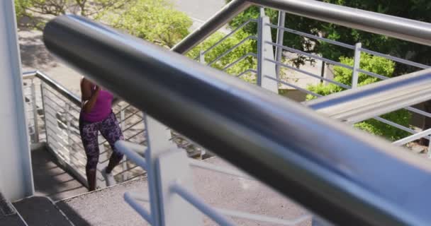 Mujer Afroamericana Con Auriculares Subiendo Las Escaleras Del Puente Ciudad — Vídeos de Stock