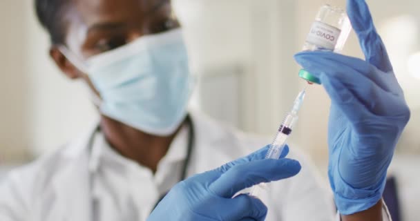 フェイスマスクを着用したアフリカ系アメリカ人女性医師は 患者のために咳止めワクチンを準備する コロナウイルスの専門医療従事者は19のパンデミックを克服しました — ストック動画
